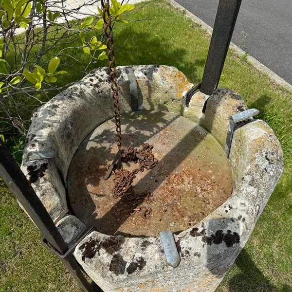 antique stone well head with chain, pulley and gantry